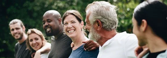 people standing with their arms around each other in a line, all happy and laughing.