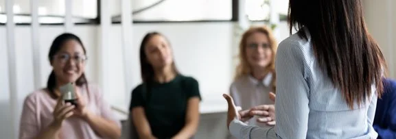 A trainer presenting to a trainees who are listening intently. 