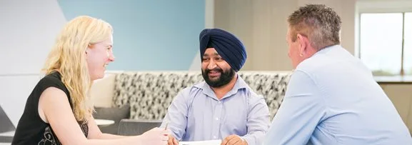 A group of three staff having a casual meeting around a table.