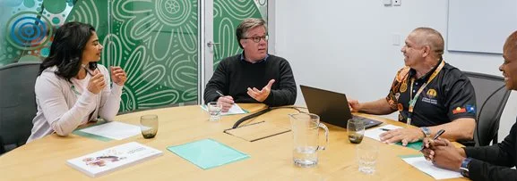 Staff sitting around a table having a meeting or discussion. 