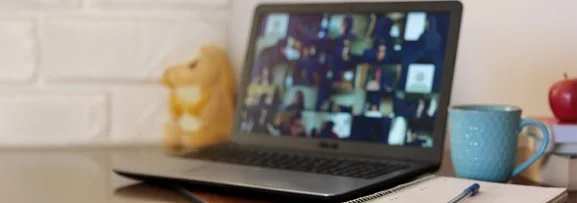 A laptop and notebook showing someone attending an online webinar.