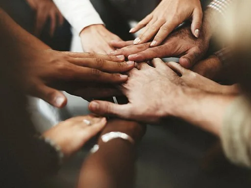 people all putting their hands in to show collaboration.