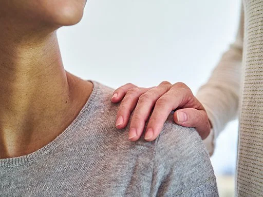 Someone with hand on their shoulder in show of support. 