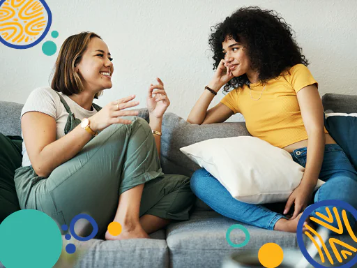 Two young people sitting on a couch talking. 