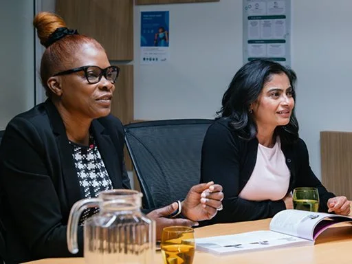 Two female staff engaging in a meeting in the workplace.