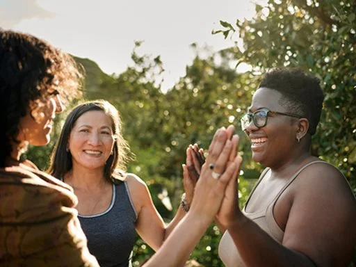 A group of women standing in a circle supporting each other.