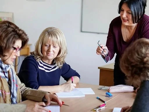 Women sitting in discussion with a trainer and completing a training activity.