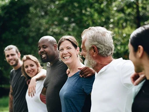 people standing with their arms around each other in a line, all happy and laughing.