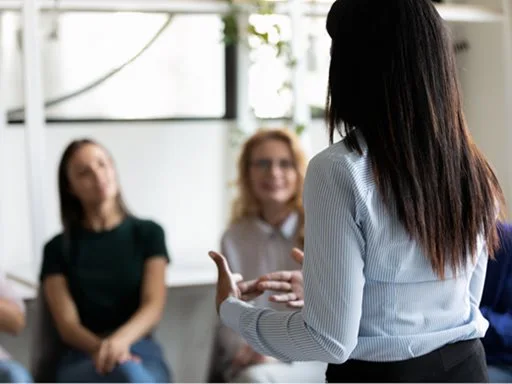A trainer presenting to a trainees who are listening intently. 