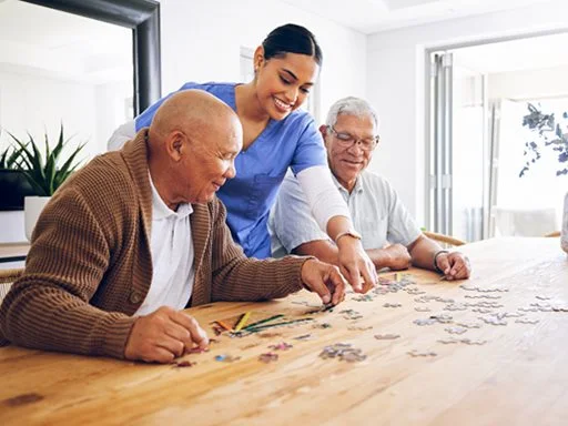Two elderly men doing a puzzle with a support worker. 