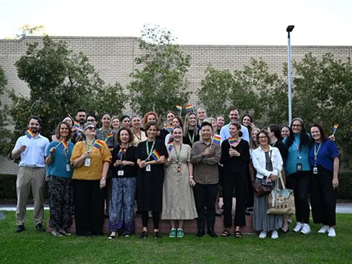 Mental Health Commission staff standing for a group photo, holding LGBTI+ flags.