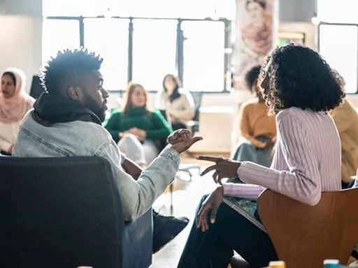 People sitting in a circle having a group discussion as part of their training.