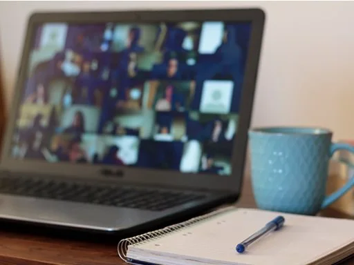 A laptop and notebook showing someone attending an online webinar.