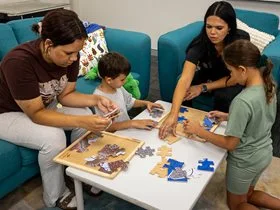 Three children of varying ages doing a puzzle with an Aboriginal mental health worker.
