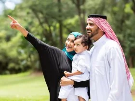 A mother and father happily spending time together outside with their toddler.