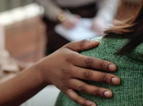 person with hand on someones back in support