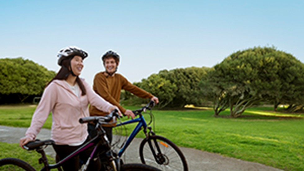 Two people on bicycles riding through a grassy park.